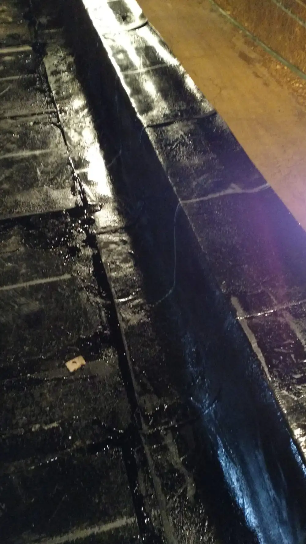 Base sheet being mopped into hot asphalt on a flat roof
